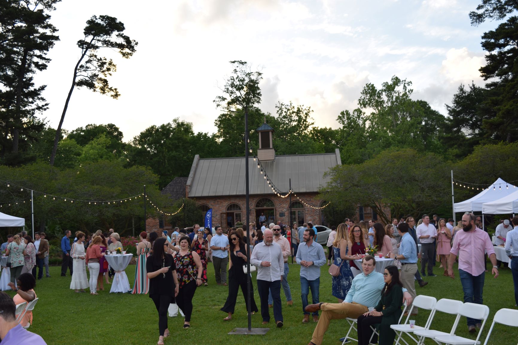 Gourmet in the Gardens guests are walking around the gardens while they eat and drink gourmet food and cocktails. They are smiling and enjoying the beautiful garden atmosphere