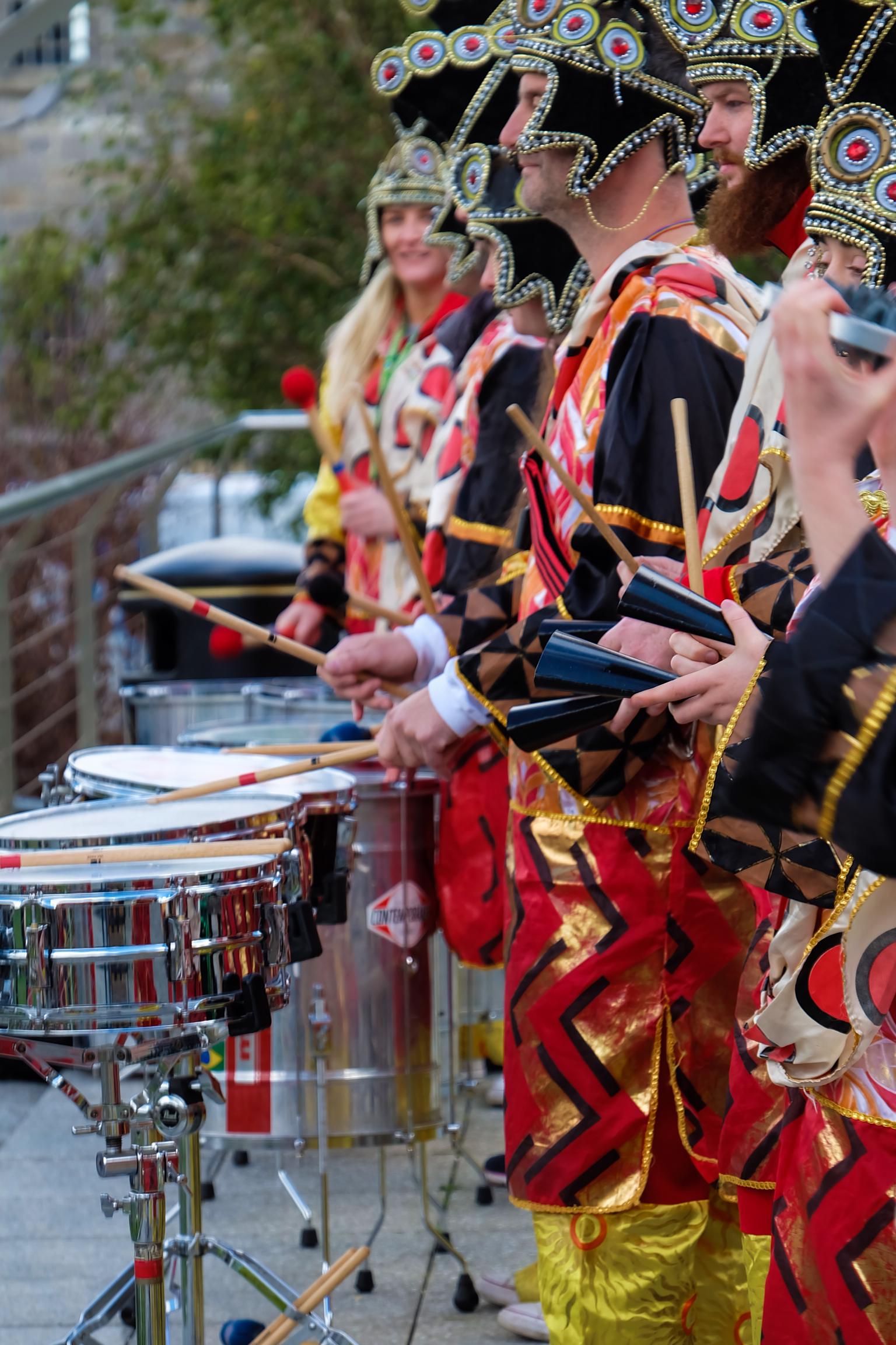 SAMBA BAND IN COLOURFUL SEQUENCED COSTUMES AND HEADDRESS PLAYING MUSIC AT VEGFEST.