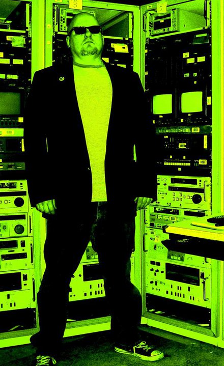 Ollie of Trapezoids in front of a wall of old electronics