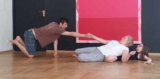 Kneeling man reaching out for 2 women on floor