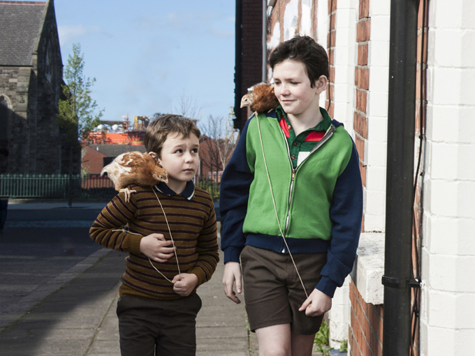 film still of two young boys walking with birds on their shoulders