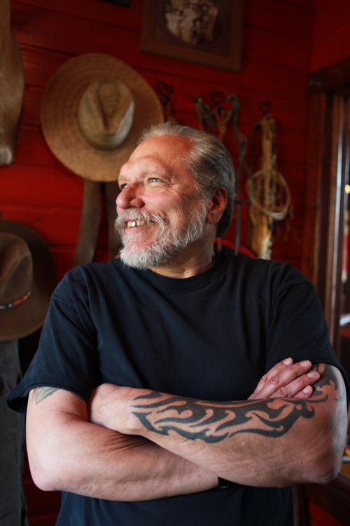a portrait of jorma kaukonen with his arms crossed
