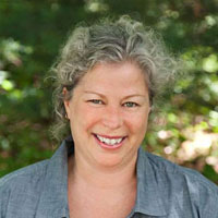 a woman with gray hair and blue shirt smiling