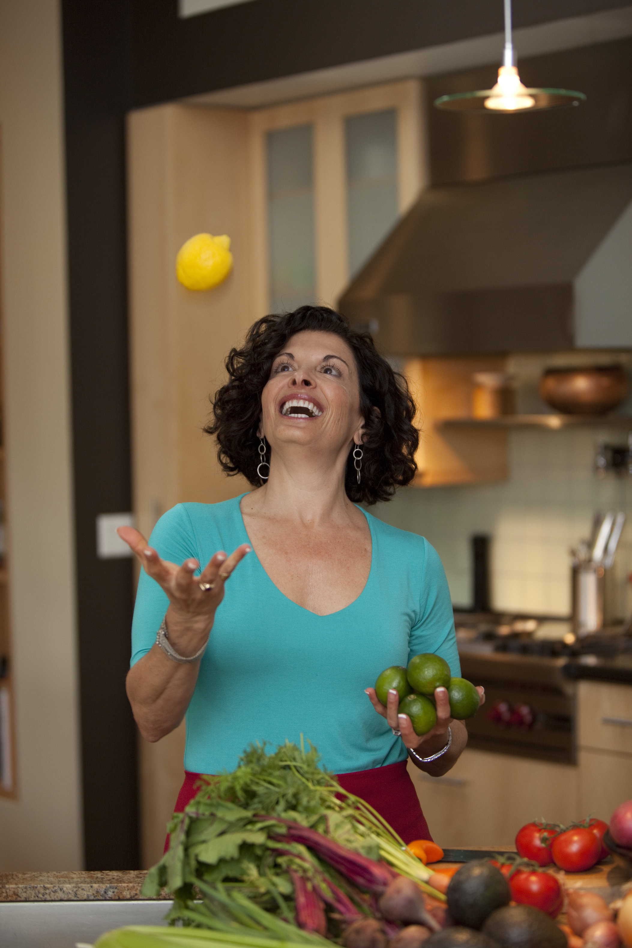 a woman tossing a lemon into the air in a kitchen setting, she is joyful