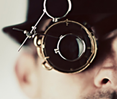 Mystery man holds antique Eye Loupe magnifying glass in front of eye