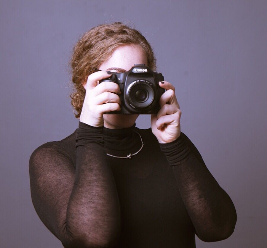 Woman in black with camera in front of face