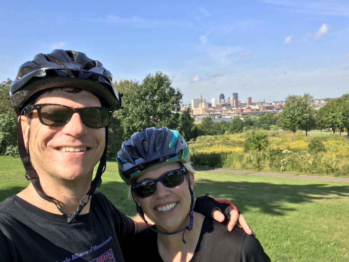 Two bicyclists stop for a selfie with a view of Downtown Saint Paul.